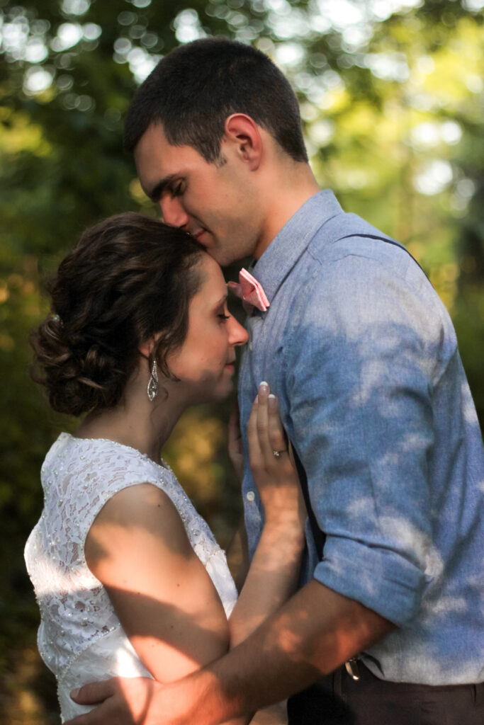 young couple holding each other on wedding day in woods