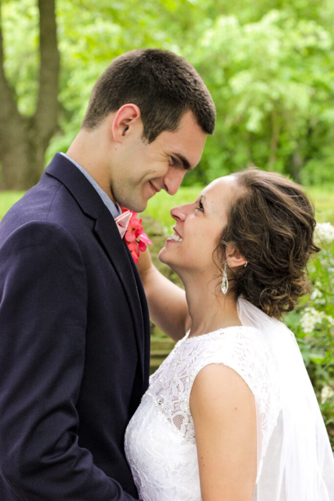 young couple holding each other on wedding day in woods smiling