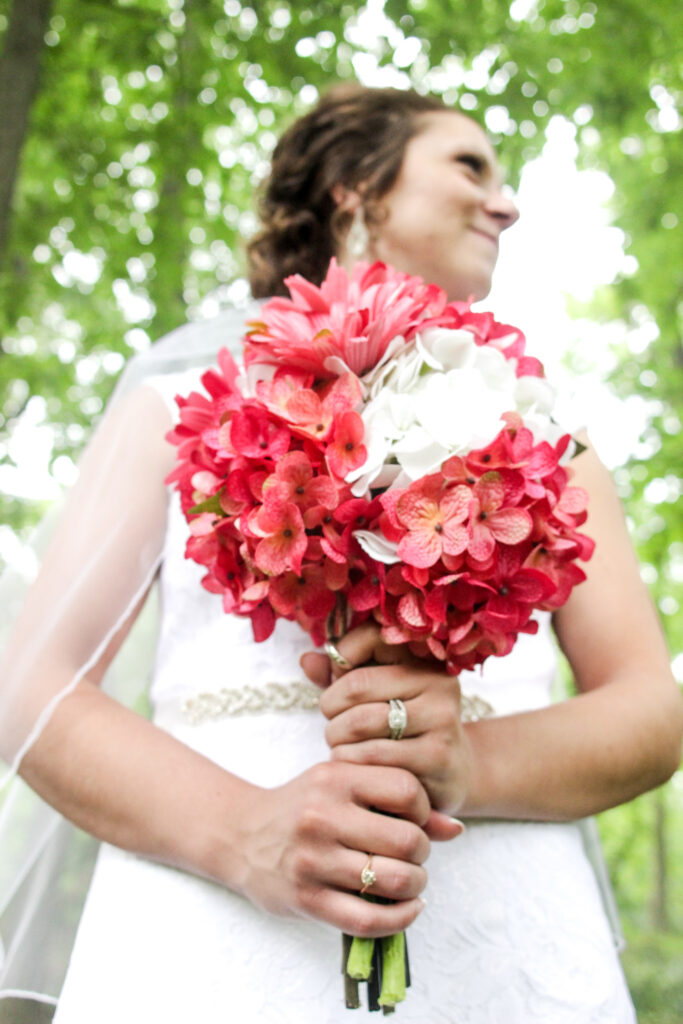 young bride holding bouquet with important family rings on her fingers in woods