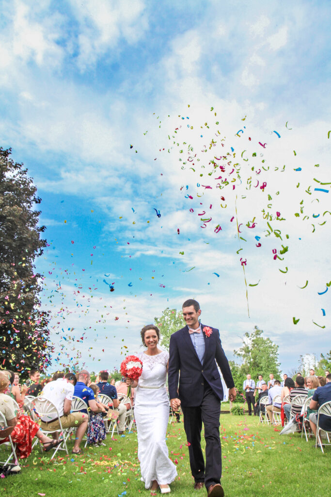 young couple on wedding day walking down aisle together with confetti in the air