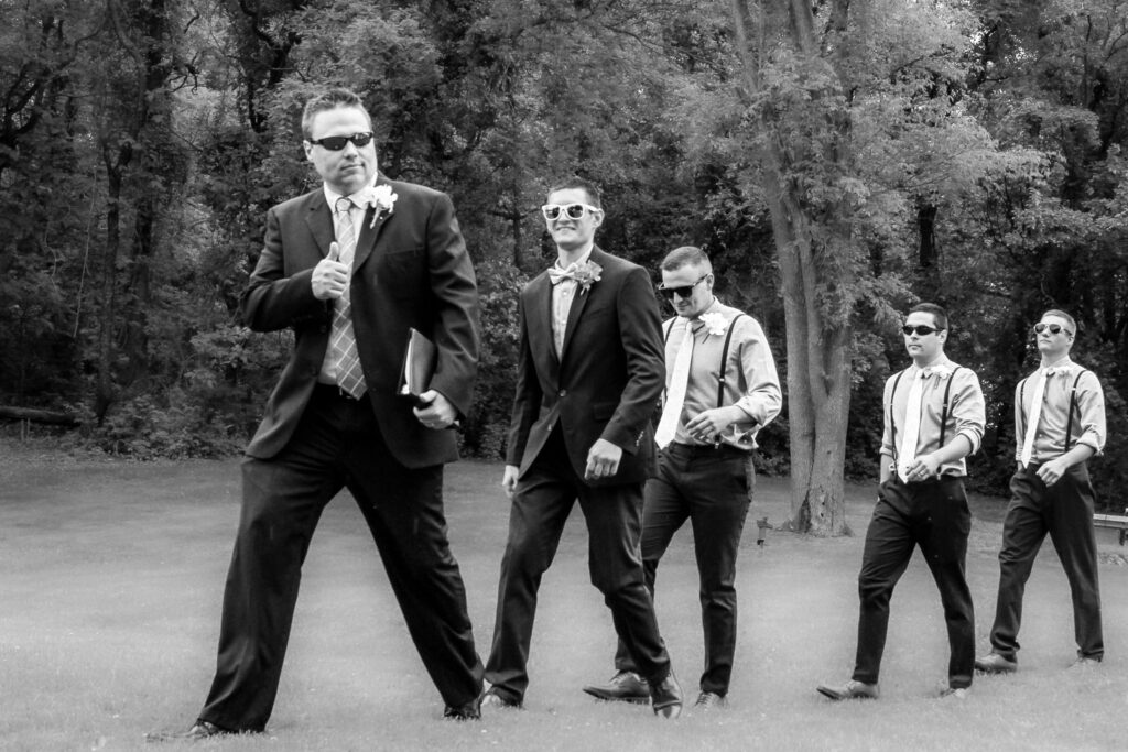 Pastor, groom, and groomsmen walking to alter in sunglasses, pastor gives thumbs up