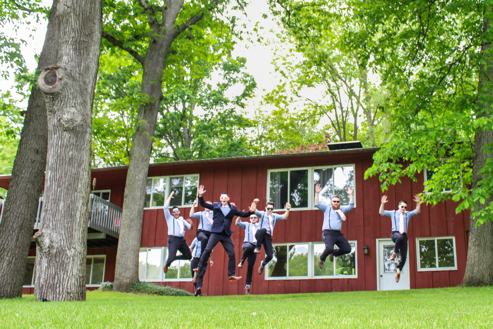 groom and groomsmen jumping in air with sunglasses on