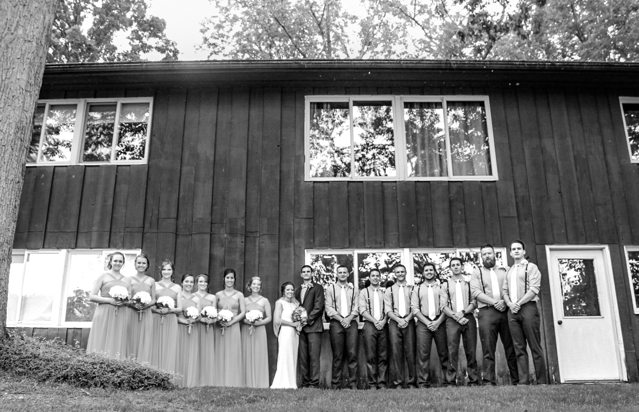 Bridal party all posed together in front of converted barn smiling