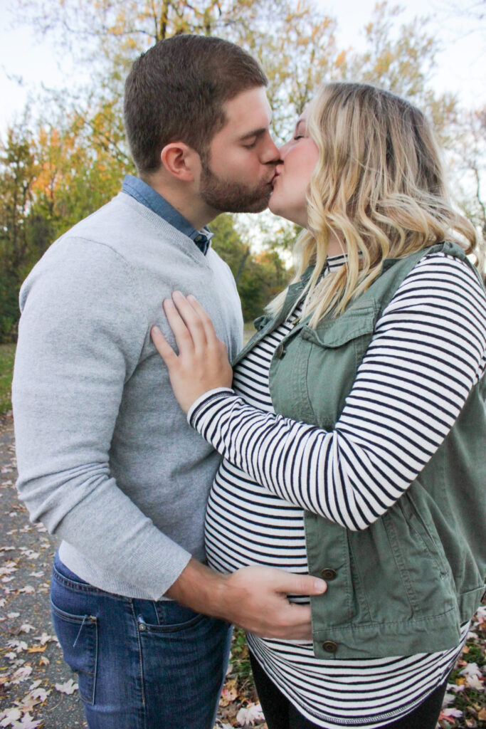 Couple kissing each other, husband's hand is on wife's pregnant belly