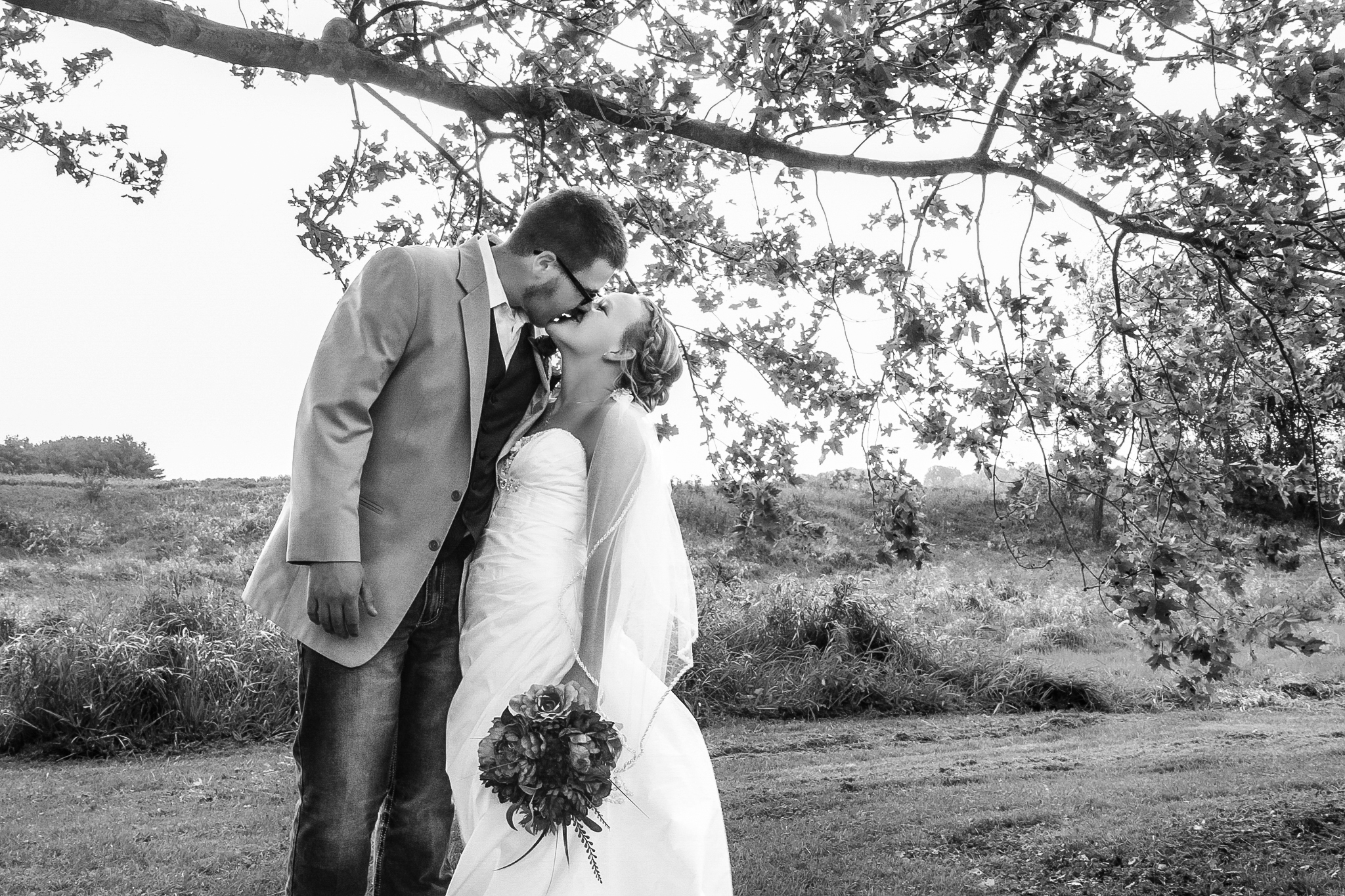 Groom and bride kiss by tree