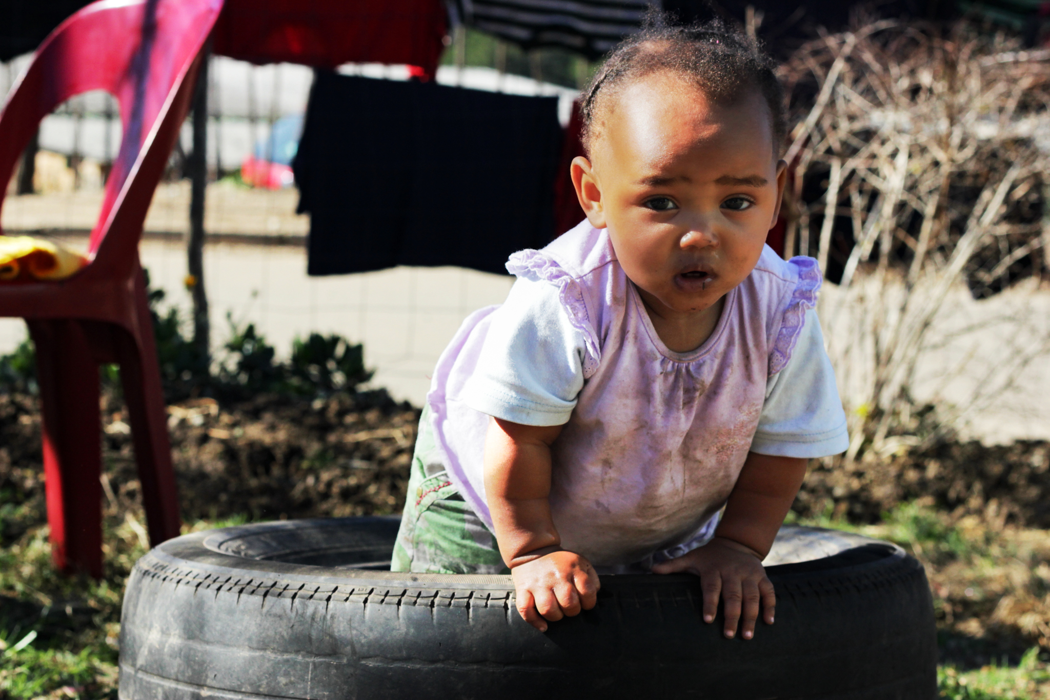 Toddler from Blanco township in Goerge, South Africa standing inside a tire on the ground