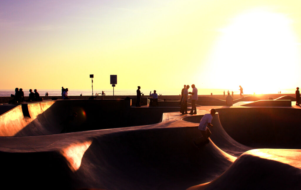 Multiple skateboarders in Venice Beach Skate Park next to the ocean during sunset in Venice Beach, California