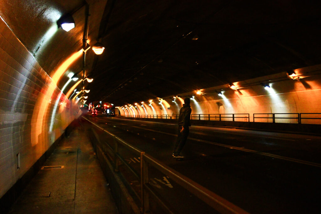 Young man skateboards down road in a tunnel in San Francisco