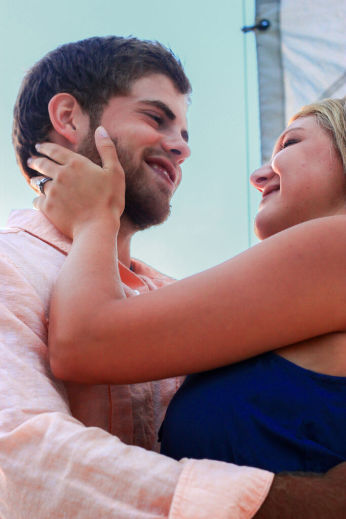 Young couple hold each other on sailboat, woman holding face of man, both smiling