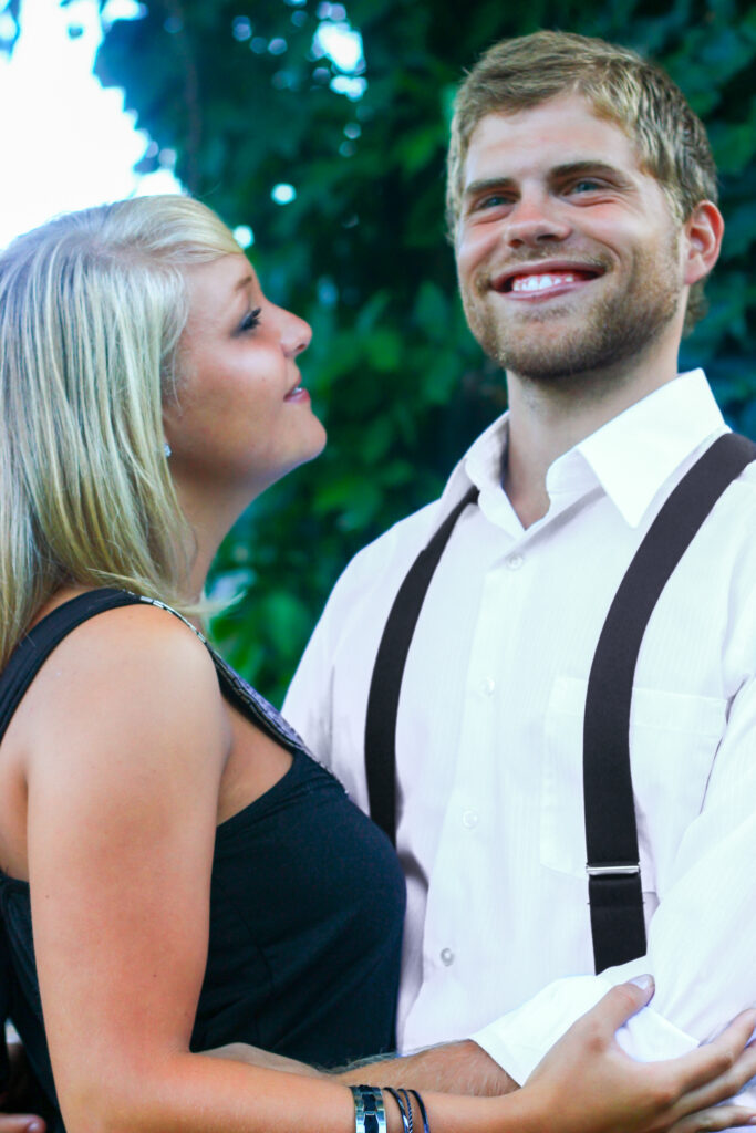 Young couple hold each other, man is smiling while woman looks at him