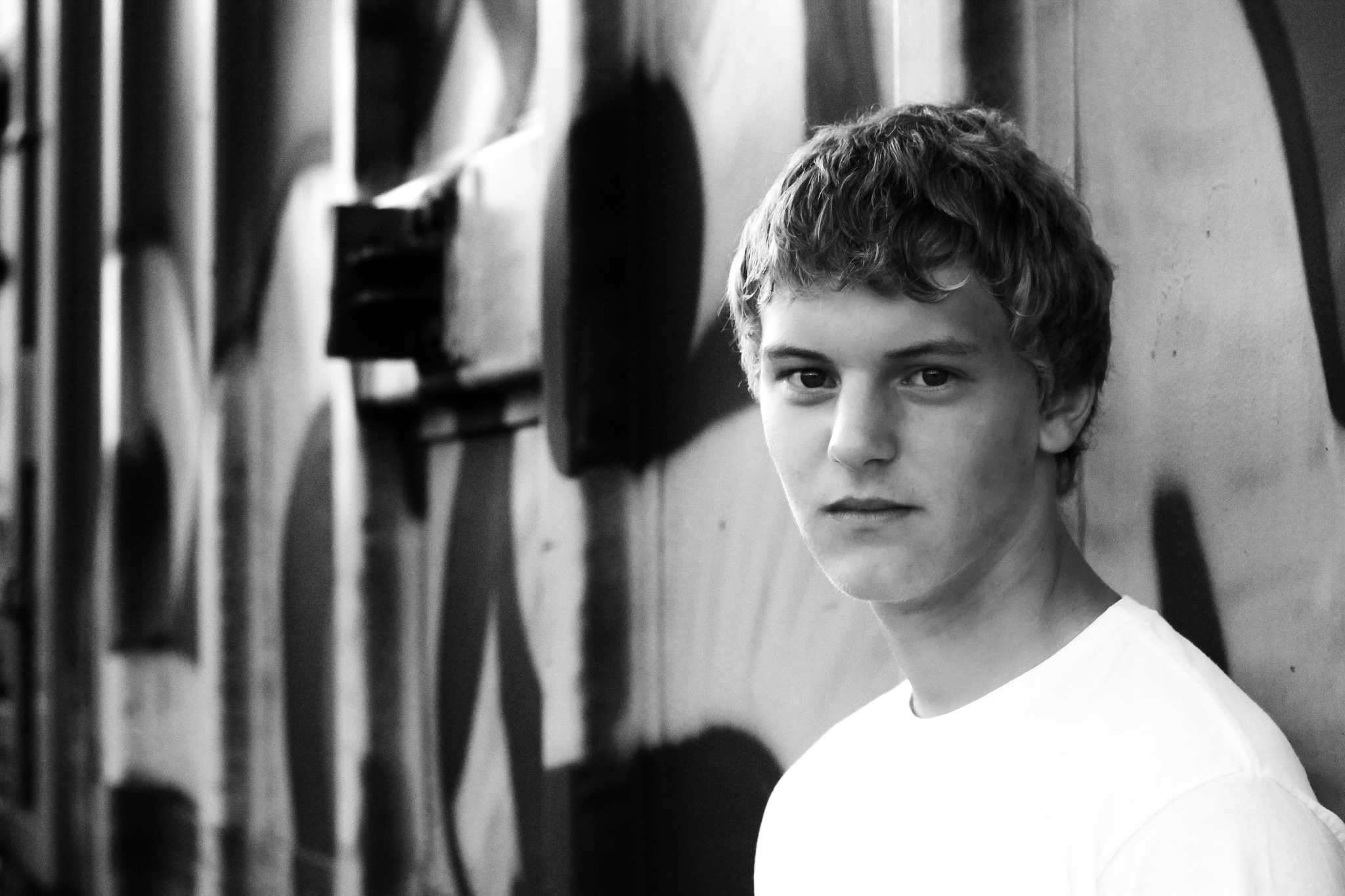 Young man leans against railcar with graffiti for senior photo