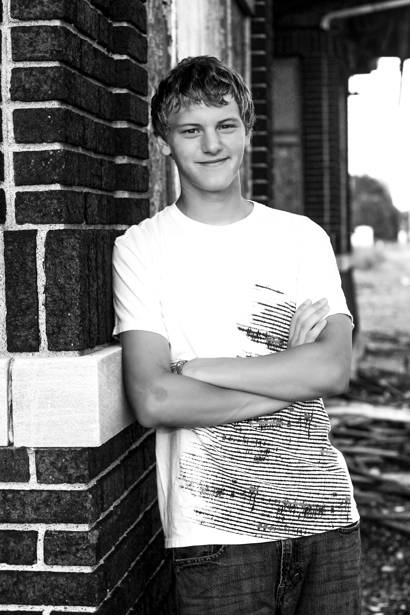 Young man leans against railcar with graffiti for senior photo and smiles