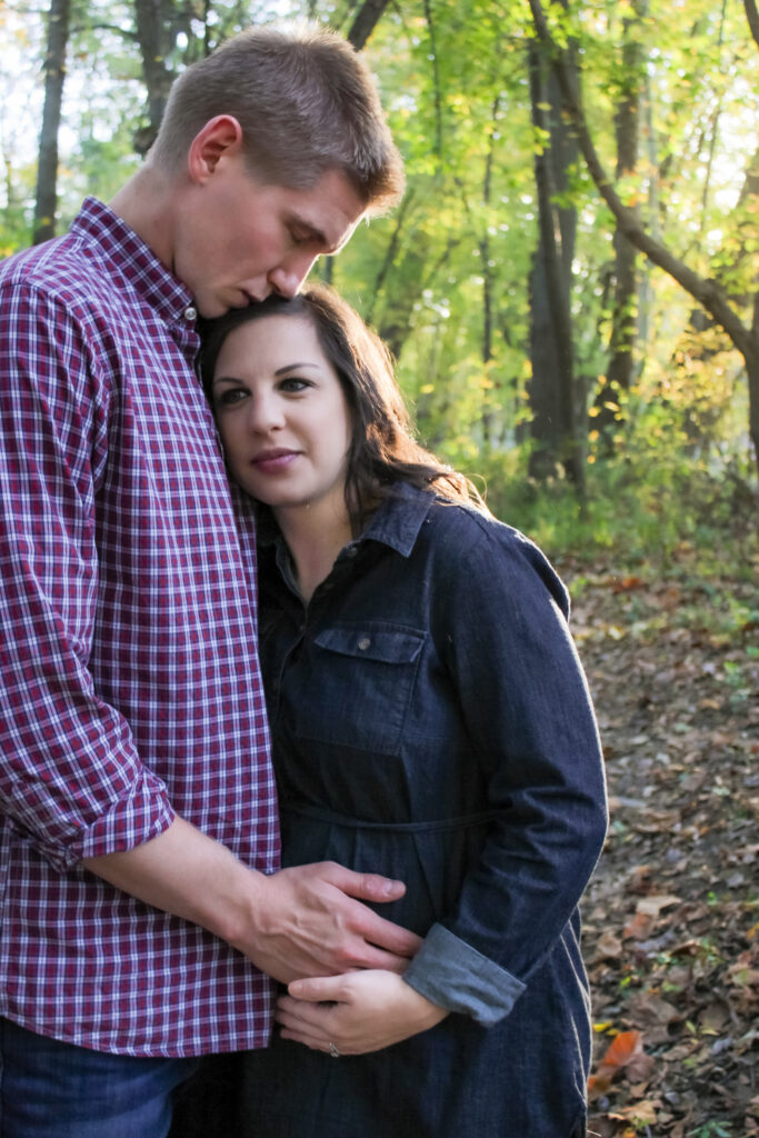 couple stand close together and hold mom-to-be's belly