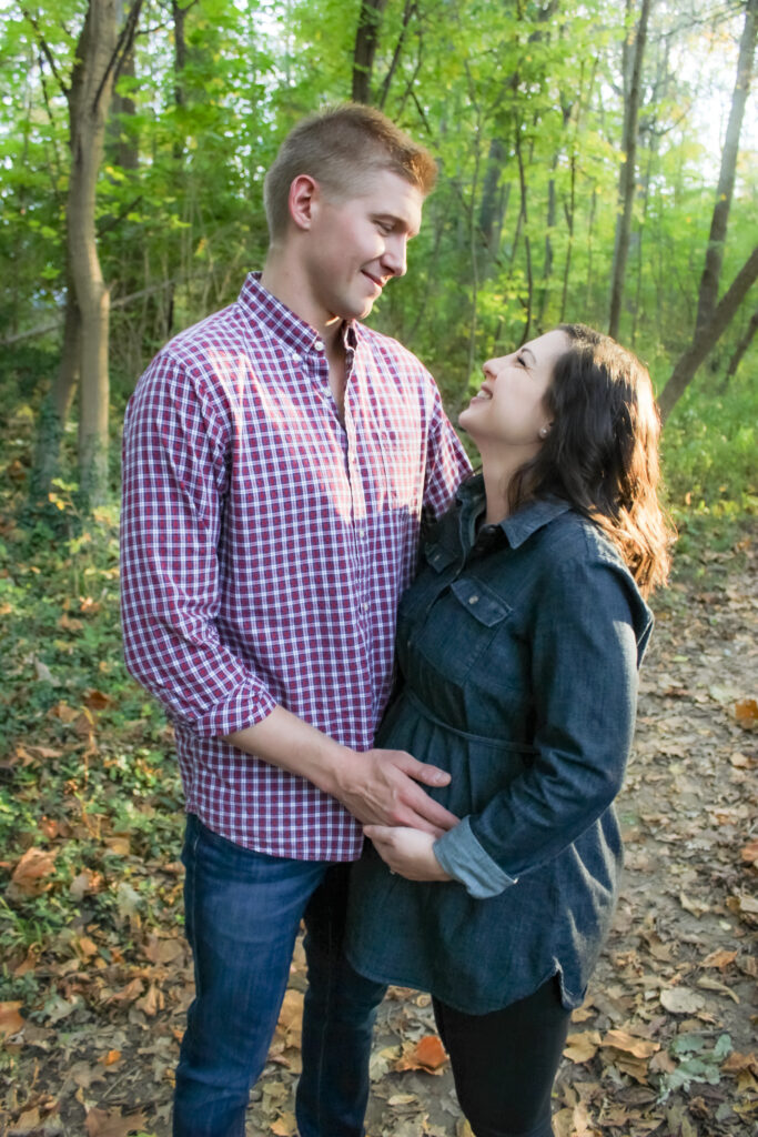 couple stand close together and hold mom-to-be's belly and smile at each other