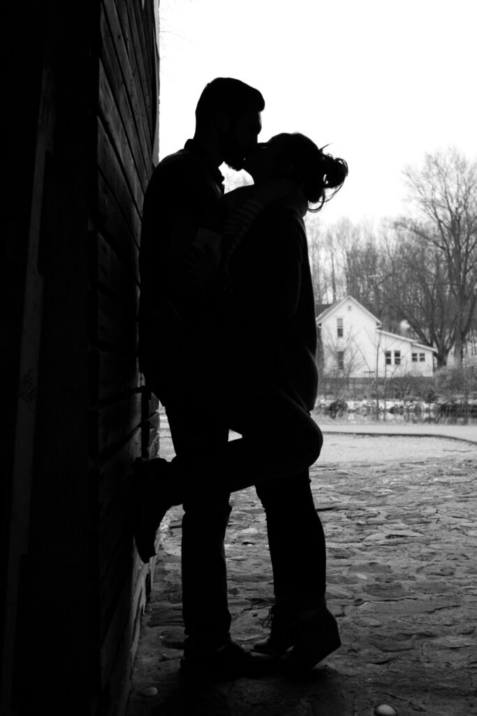 Young couple silhouetted, kissing against wall
