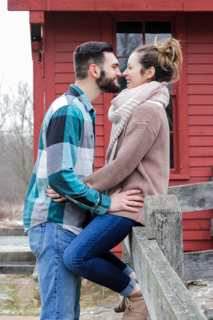 Young couple facing each other, girl is sitting on fence and boy is facing her