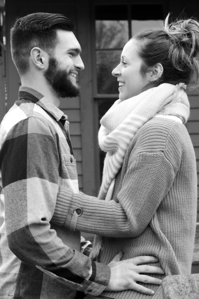 Young couple facing each other, girl is sitting on fence and boy is facing her