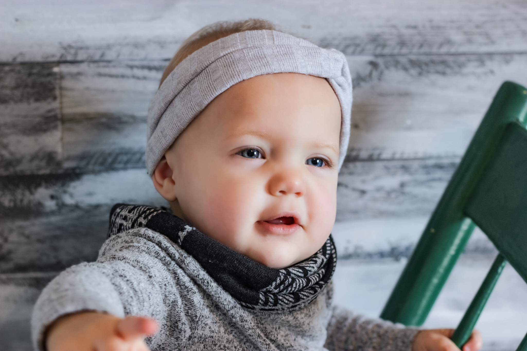 one year old girl sits sits on old wooden rocking chair