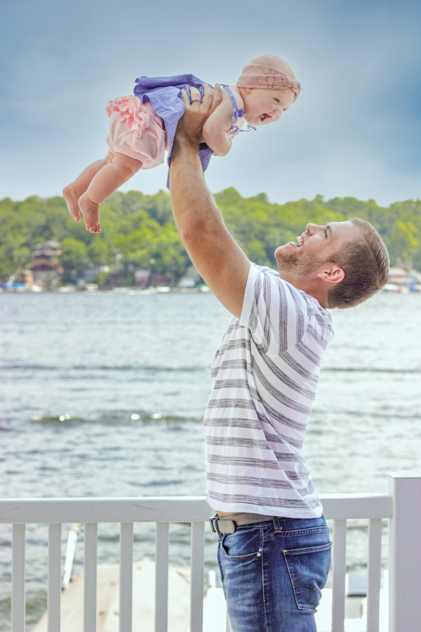 Family photographs, dad holding baby daughter up in the air, both laughing