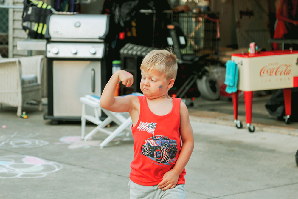 Young boy flexes bicep while looking at it