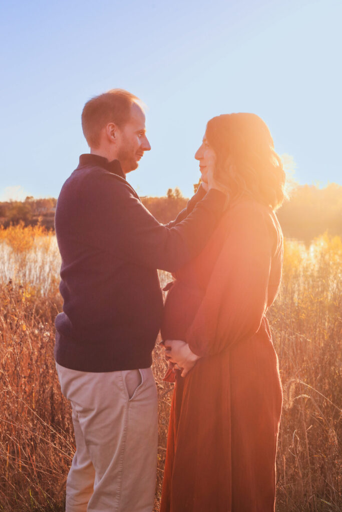 pregnant couple n sunset, wife holds belly