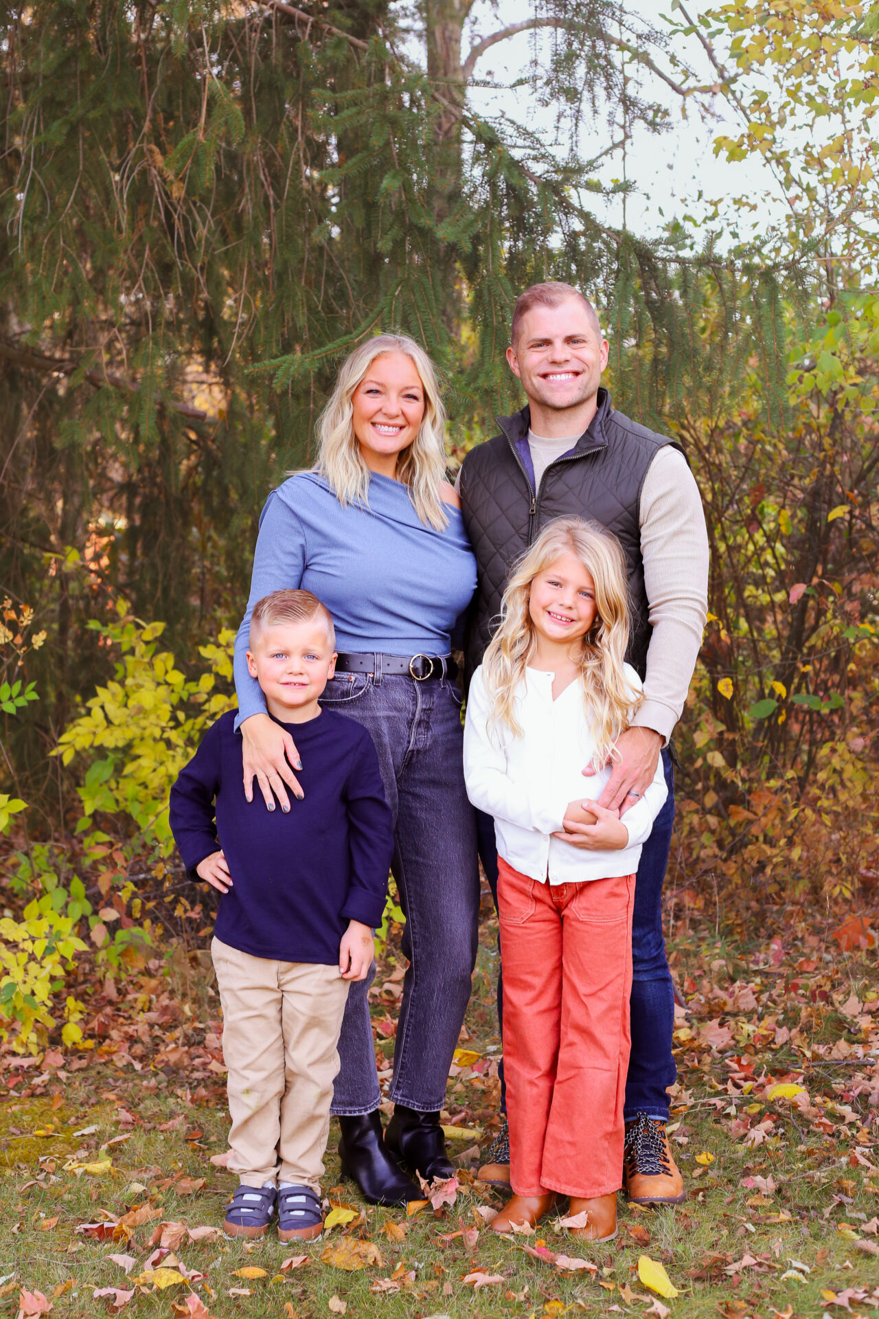 young family of four smiles for camera in autumn