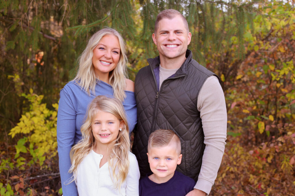 young family of four smiles for camera in autumn