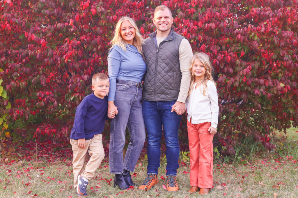 young couple stands with two young children and smile at the camera