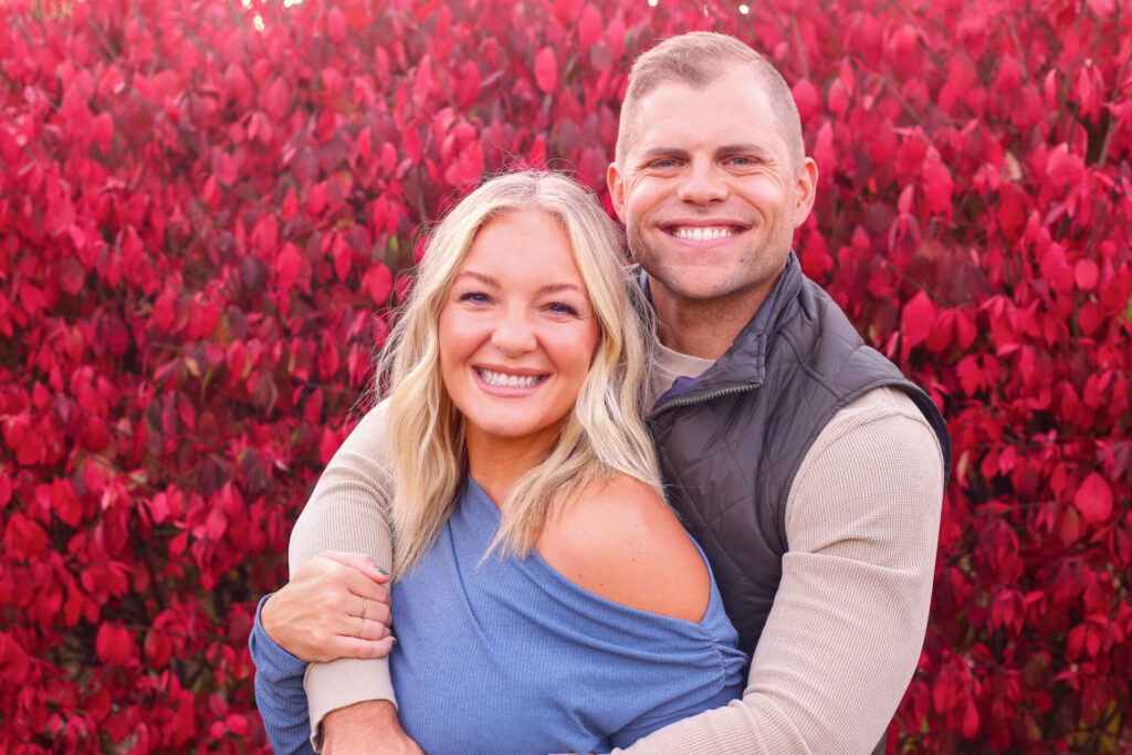 young couple hold each other and smile at camera